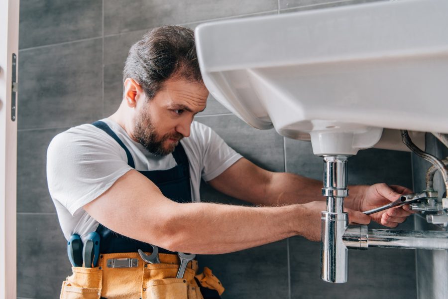 focused-male-plumber-in-working-overall-fixing-sink-in-bathroom.jpg focused-male-plumber-in-working-overall-fixing-sink-in-bathroom.jpg